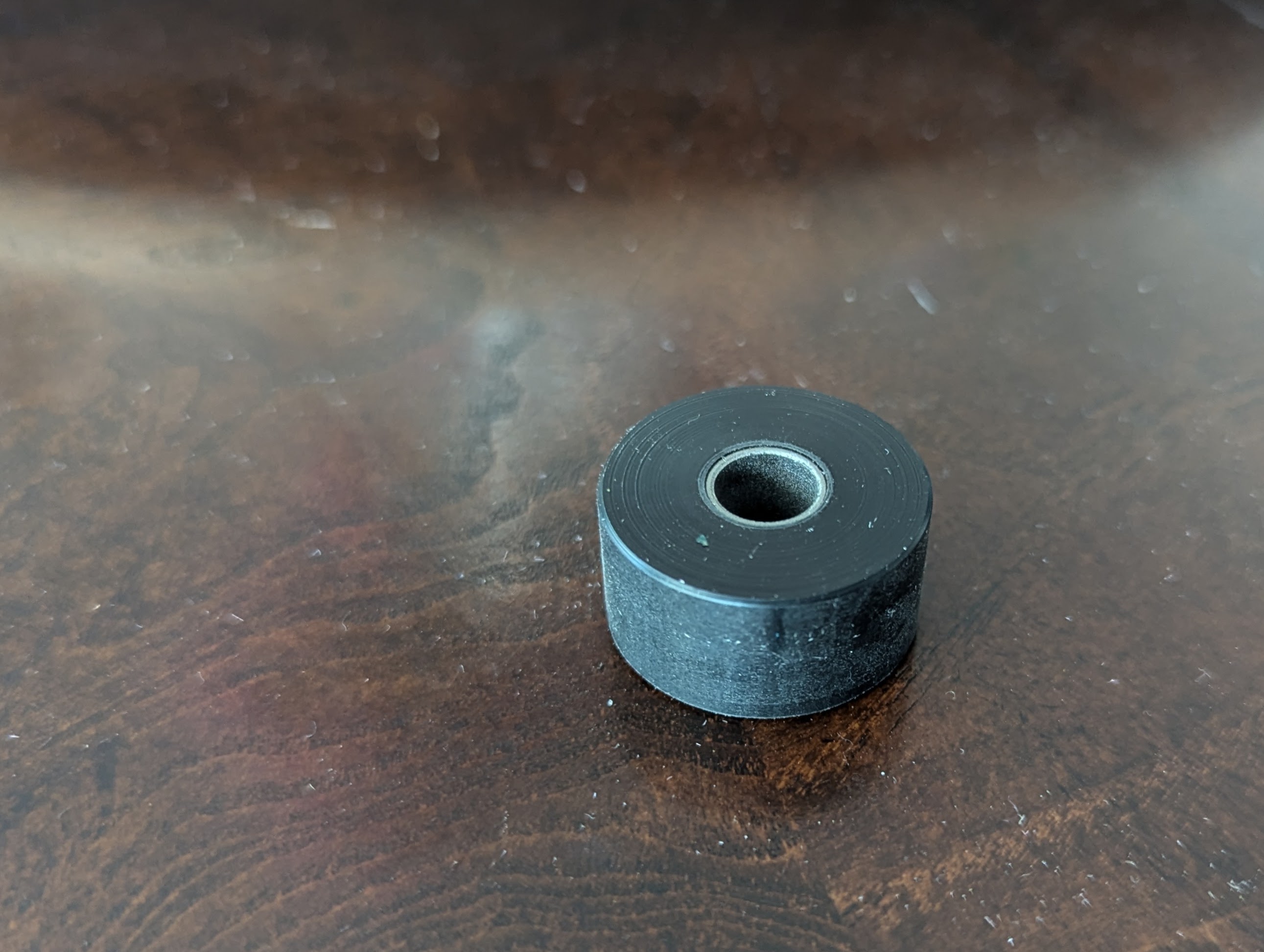 Close-up of a new machined black plastic wheel with metal sleeve bearing installed.