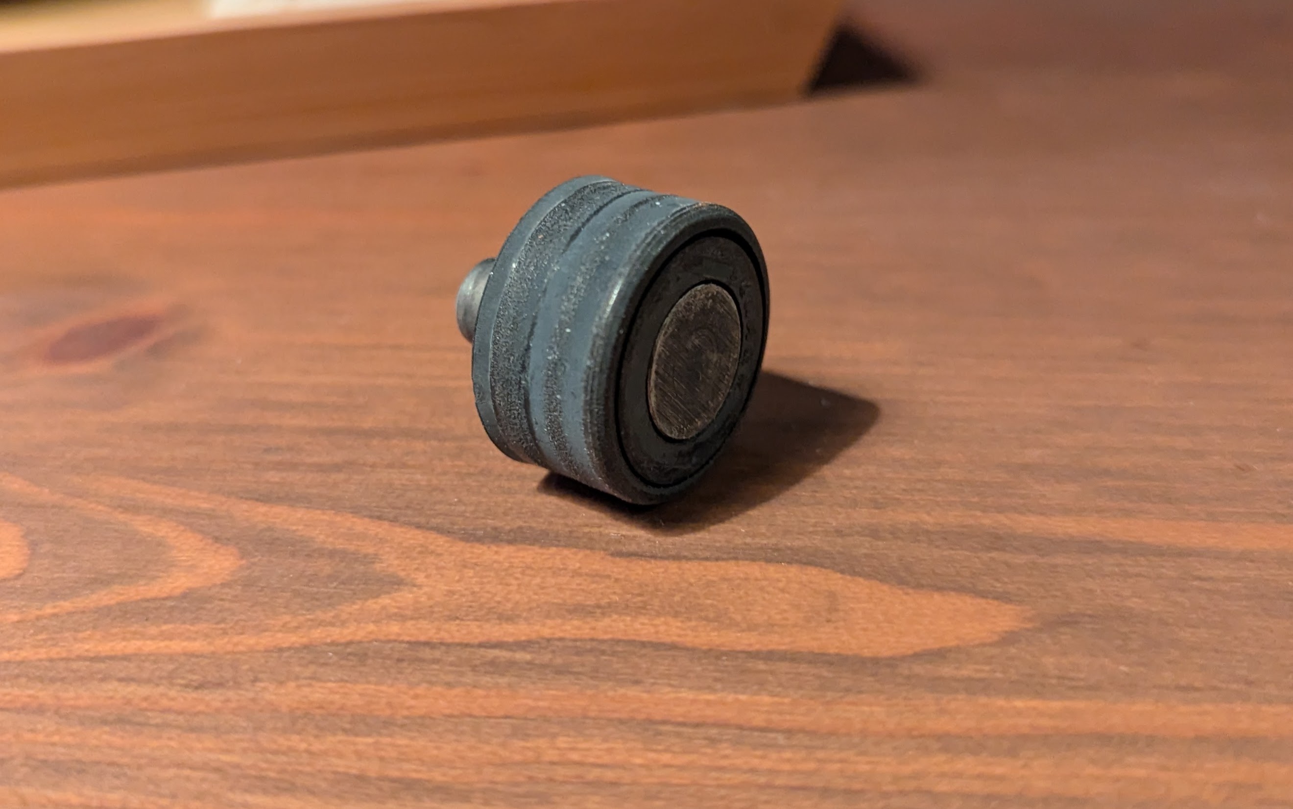 Close-up of a plastic wheel on a metal axle; wheel shows significant wear.